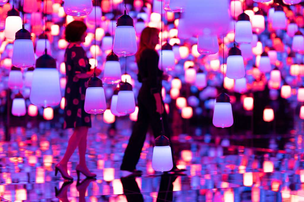 Visitors walking among glowing hanging lamps at teamLab Borderless, Tokyo, Japan